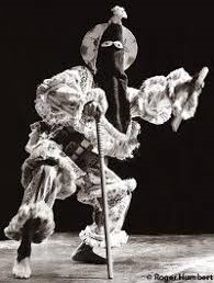 Íreme dancer in a full Abakuá costume with cone-shaped hood, holding a stick